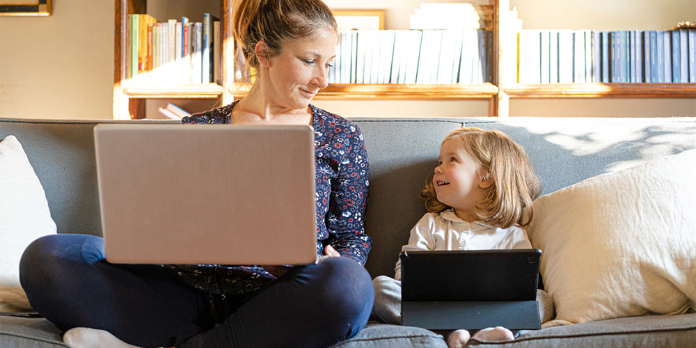 Mutter im Homeoffice mit Kind auf dem Sofa