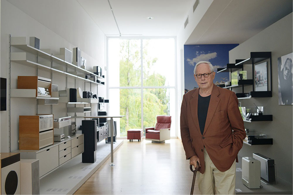 Dieter Rams steht im Raum vor seinen Werken