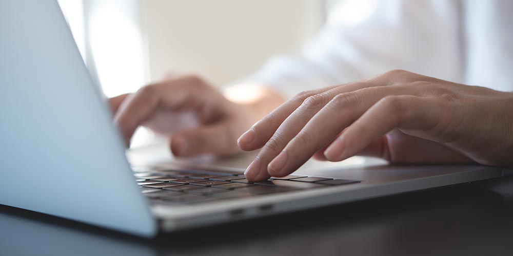 Hände tippen auf einer Laptop-Tastatur, Bild: iStock/TippaPatt