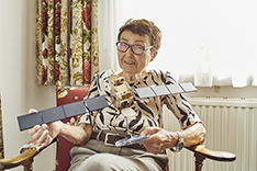 Eveline Gottzein sits on a chair and holds a satellite model