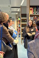 weibliche Azubi erklärt in der Bibliothek vor interessiertem Publikum