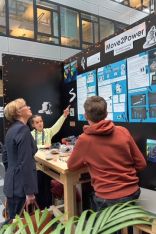 drei Personen vor Projektplakat im Gespräch