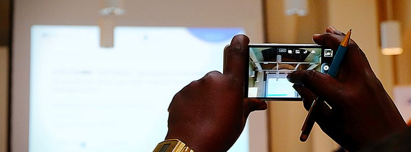 zwei Hände von Person mit Migrationshintergrund fotografieren mit Handy