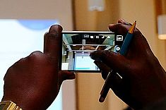 Two hands of person with migrant background taking a picture using a mobile phone