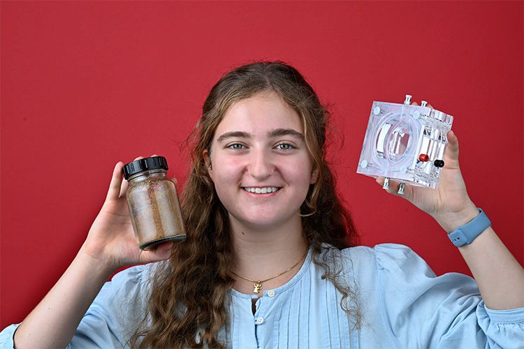 Junge Frau hält Glasbehälter mit organischem Material und galvanische Zelle in den Händen