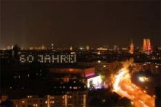 DPMA headquarters illuminated at night, windows spelling "60 years"