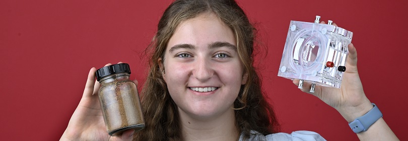 Junge Frau hält Glasbehälter mit organischem Material und galvanische Zelle in den Händen