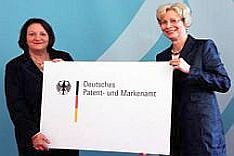 Zwei Frauen präsentieren ein Schild mit aufgedrucktem Logo