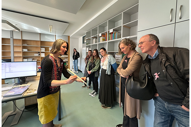 Bibliotheksmitarbeiterin zeigt ein Maßpapier für einen Bucheinband
