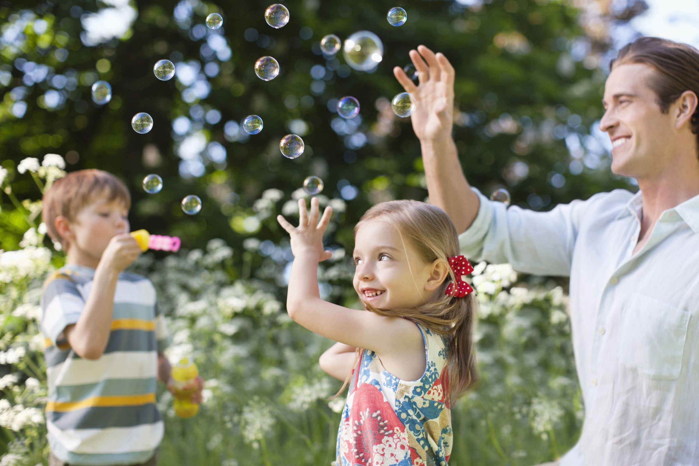Kinder und Vater freuen sich über Seifenblasen