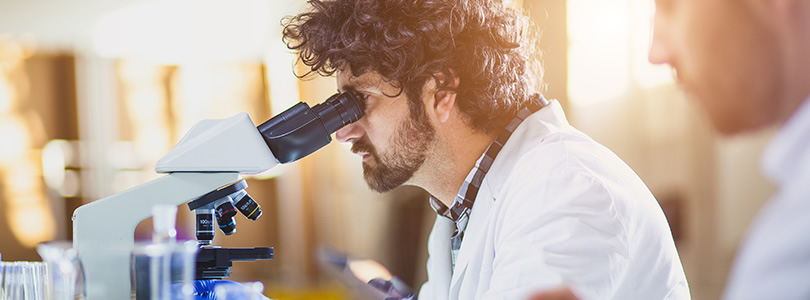 Forscher schaut in ein Mikroskop