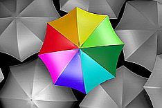 A colourful umbrella amidst grey ones