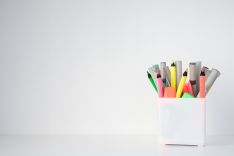 Bunte Stifte in weißem Behälter vor weißem Hintergrund