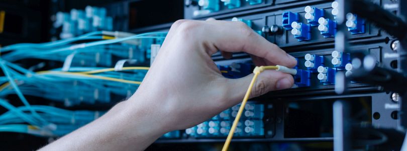 Hand steckt ein Kabel in Serveranlage