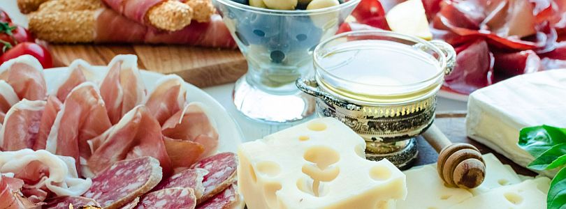 gedeckter Tisch mit Salami, Schinken, Käse und Wein