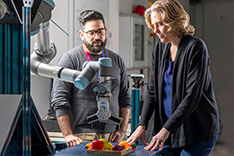 Woman in front of robotic arm that captures vegetables 